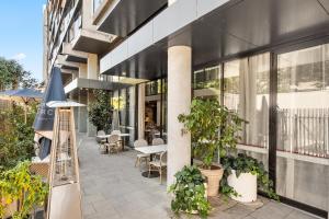 an outdoor patio with plants and tables and a building at Stylish Central Braddon 1 Bed, Pool, Gym, Parking in Canberra
