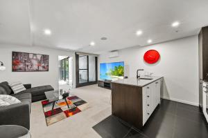 a living room with a couch and a tv at Stylish Central Braddon 1 Bed, Pool, Gym, Parking in Canberra