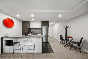 a kitchen with a counter with chairs and a table at Stylish Central Braddon 1 Bed, Pool, Gym, Parking in Canberra +11 photos