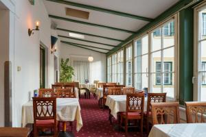 ein Esszimmer mit Tischen, Stühlen und Fenstern in der Unterkunft Altstadthotel Eck in Lienz