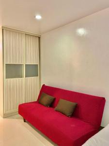 a red couch with two pillows on it in a room at 2B-15 Condo Staycation at Megatower 1 in Baguio