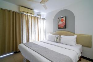a bedroom with a bed with white sheets and a window at Olive Zip Calangute Mira by Embassy Group in Calangute