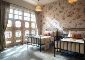a bedroom with two beds and floral wallpaper at LohonoStays Calisto Villa E in Camorlim