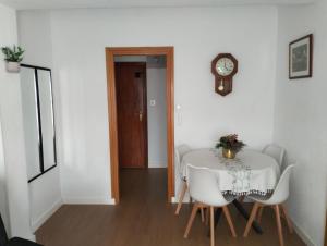 a dining room with a table and chairs and a clock at Ricardo Hostal Apartamento in Alicante