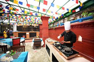 a chef preparing food on a stove in a restaurant at Tibet Boutique Hotel Annex in Kathmandu
