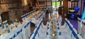 a long table with white tables and blue chairs at Landhotel Thürmchen in Schirgiswalde
