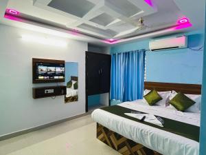 a bedroom with a bed with a tv on the wall at Hotel ANR Grand in Visakhapatnam