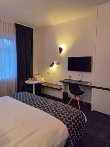 a hotel room with a bed and a desk and a tv at Let's Meet Elewijt in Elewijt +69 photos