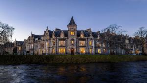 an old building with a clock tower next to a river at The Ambassador Hotel in Inverness