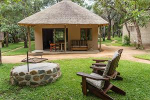 a gazebo with a bench and a table and chairs in a yard at Shumba Safari Bush Camp in Hoedspruit