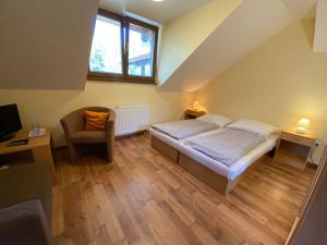 a small bedroom with a bed and a chair at Penzión na Ráztočnom in Klenovec