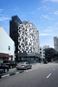 a building with a bunch of cars parked in front of it at Amrise Hotel Kitchener, Check In 9PM, Check Out 8AM in Singapore