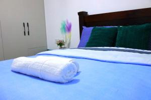 a white towel laying on a blue bed at GBSL Grand Villa in Nairobi
