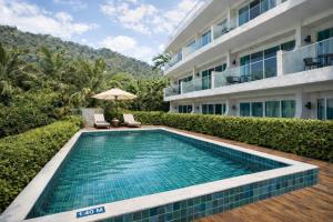a swimming pool in front of a building at Santosa Hotel & Welness Center in Kata Beach