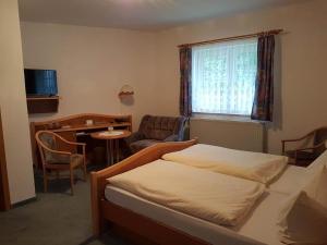 a bedroom with a bed and a table and a chair at Land-gut-Hotel Zur Lochmühle in Penig