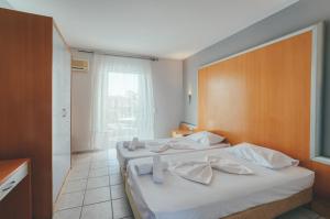 a bedroom with two beds with white towels on them at Mojo Hotel Laganas Zante in Laganas