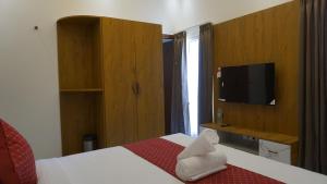 una camera d'albergo con un letto e una televisione di Hanee Comforts a Chikmagalūr
