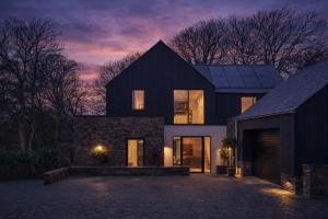 a large black house with a garage at night at Finest Retreats - Orchard Rise in Bude