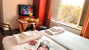 two beds in a room with a tv and a table at Double room H Požarevac in Požarevac