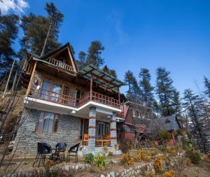 a house with chairs in front of it at Ishan Log Huts-A boutique home stay in Banjār