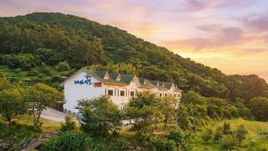 a large white building on a hill with a mountain at Tongyoung Macaio Pension in Tongyeong
