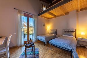 a bedroom with two beds and a table and a window at Alloggi agrituristici Paraschos in San Floriano del Cóllio