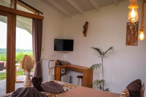 a living room with a television and a table with a desk at EDEN Private Pool Suites and Panoramic Agung View - ADULT ONLY in Nusa Penida