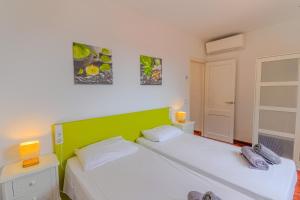 two beds in a room with green and white at Villa Betonia in Punta Prima +18 photos