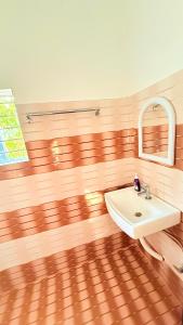 a bathroom with a white sink and a wooden floor at Serenyaa in Dibrugarh