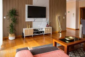 a living room with a flat screen tv on a wall at Vila Sol in Prazeres