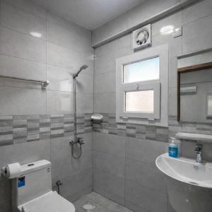 a bathroom with a toilet and a sink and a window at Majd Lux Stay in Ma‘ābīlah