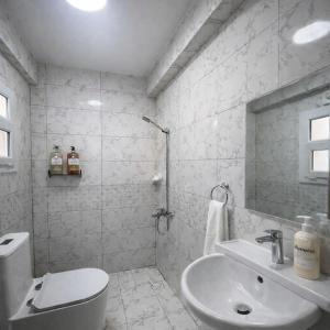 a white bathroom with a toilet and a sink at Majd Lux Stay in Ma‘ābīlah