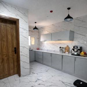 a kitchen with white marble walls and a wooden door at Majd Lux Stay in Ma‘ābīlah
