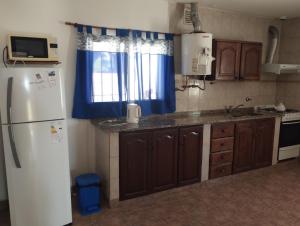 a kitchen with a white refrigerator and a blue curtain at JOAQUINA in Ramallo