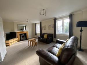 a living room with a leather couch and a tv at Spacious Bracknell Four Bedroom House in Bracknell
