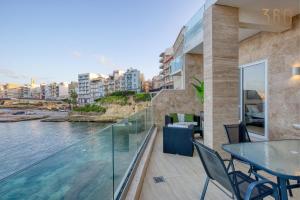 a balcony with a table and chairs and water at 2BR Seafront Elegance with Balcony & Sea Views by 360 Estates in St. Paul's Bay