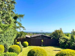 a yard with a house with a fence and bushes at Dublin Seaview Cabin in Rathfarnham