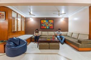 two people sitting on a couch in a living room at FabHotel Pink Cozzy in Jaipur