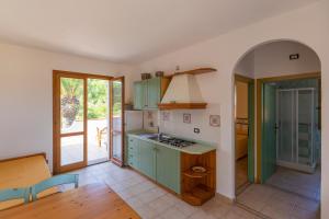 a kitchen with green cabinets and an open door at Villa Le Palme 3 - 4 in Casa Buraccio +18 photos