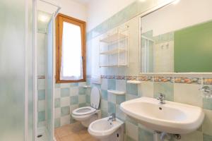 a bathroom with a sink and a toilet and a mirror at Villa Le Palme 3 - 4 in Casa Buraccio