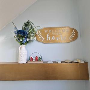 a welcome to our home sign on a shelf with a vase of flowers at Bayliss Hall in Weymouth