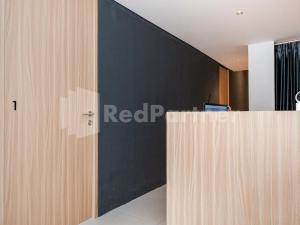 an office with a black wall and a reception desk at Mora Stay Demangan RedPartner in Yogyakarta
