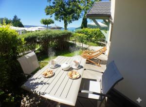 a picnic table with two plates of food on it at Reflets du Lac Annecy, Baie des Voiles - Vue Lac - Terrasse - Plage & Parking Privés in Duingt