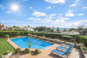a swimming pool in a yard with two blue chairs at Villa Betonia in Punta Prima