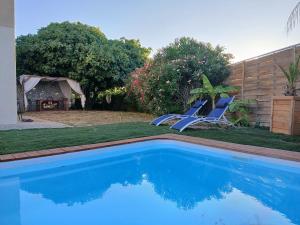 two blue chairs sitting next to a swimming pool at Air-conditioned villa with pool in Mèze