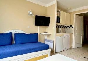 a living room with a blue couch and a kitchen at Au calme, appartement au cœur du Golf - Piscine in Talmont