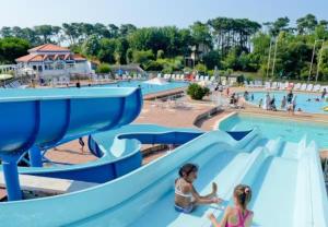 two girls on a slide at a water park at Au calme, appartement au cœur du Golf - Piscine in Talmont