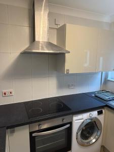 a kitchen with a stove and a washing machine at Exquisite King-sized Bedroom - Free Parking in Dartford