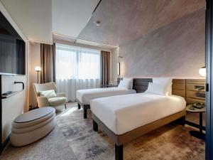 a hotel room with two beds and a chair at Novotel München Airport in Freising +114 photos