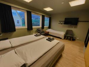 a bedroom with two beds and a flat screen tv at Gjøa Motell in Rosendal